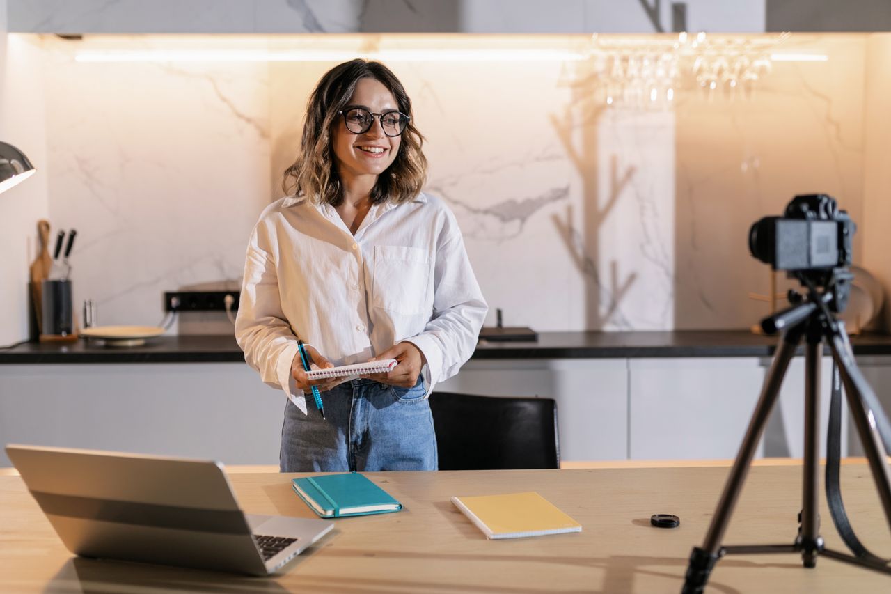 Professional woman smiling while holding a notebook in a modern kitchen setting.